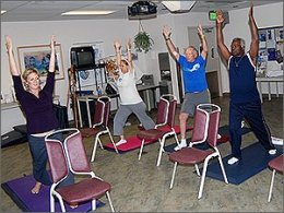 Patients and therapist performing standing yoga stretches.
